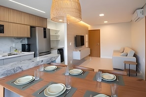 Una cocina moderna con comedor, un televisor montado en la pared y un sofá en la sala.
