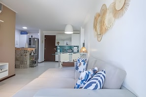 Ein modernes Wohnzimmer mit einer Couch, Wandgestaltung und einer Küche im Hintergrund.