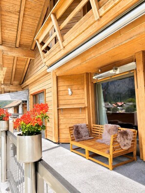 Un bâtiment en bois doté d’un balcon, d’un banc et de plantes en pot.