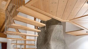 Ein modernes Interieur mit Steinkamin, Holztreppe und Marmorboden.