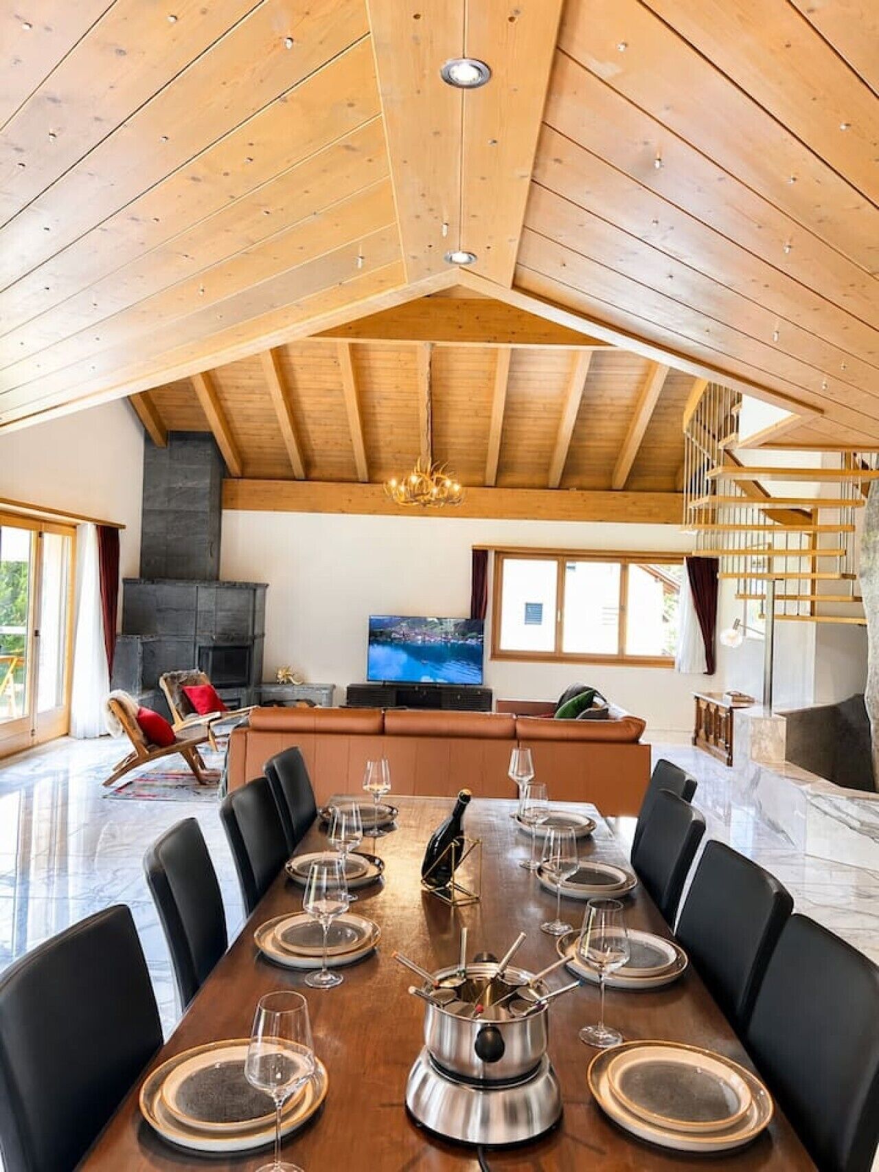 Een ruime eetruimte met een hoog houten plafond, een open haard en een televisie op de achtergrond.