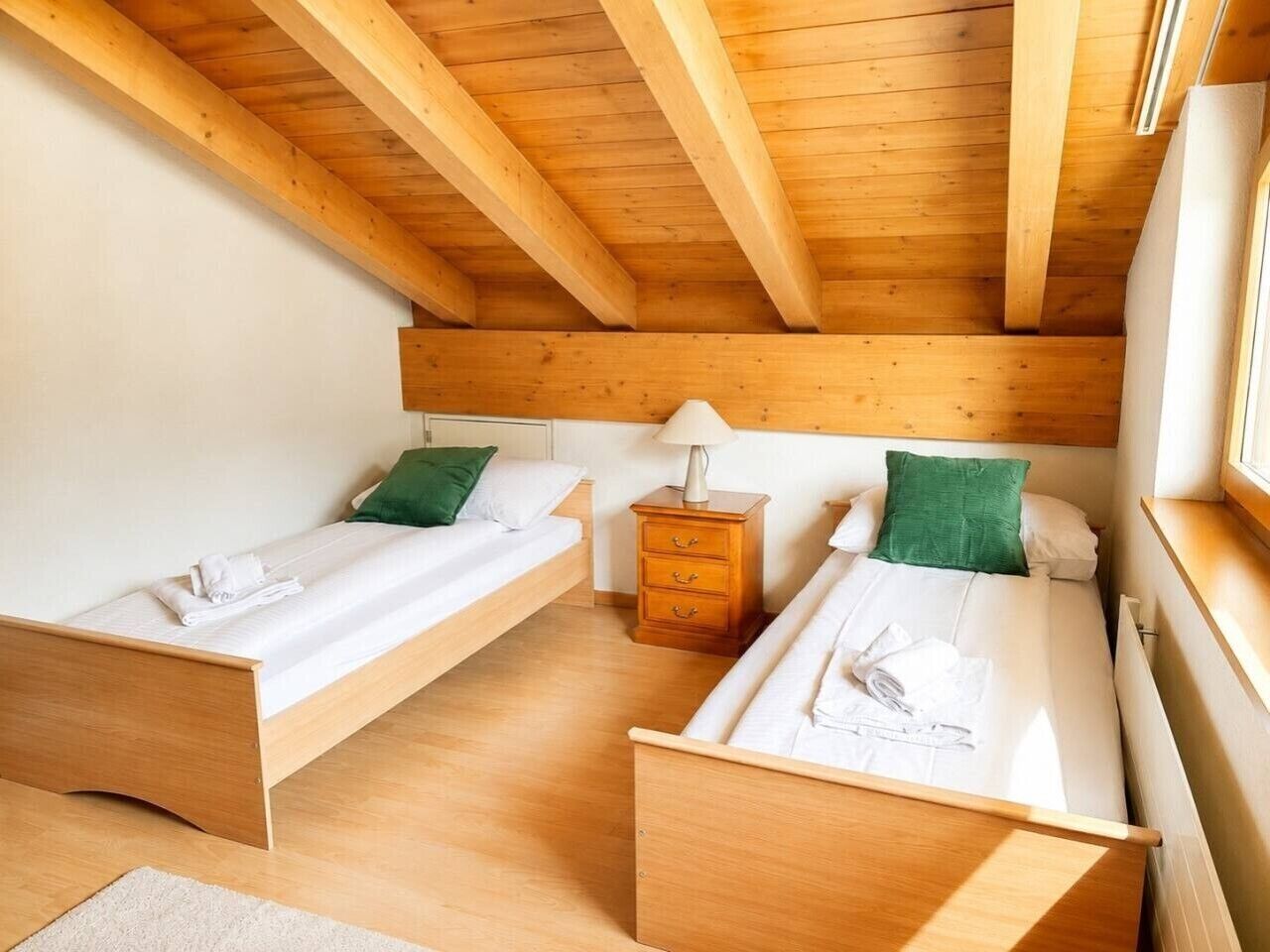 A room with two wooden beds, a nightstand, and a window.