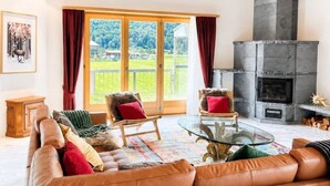 Ein geräumiges Wohnzimmer mit einem großen Ledersofa, zwei Sesseln, einem Glastisch und einem Kamin.