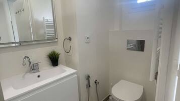 A bathroom with a white sink, mirror, and toilet.