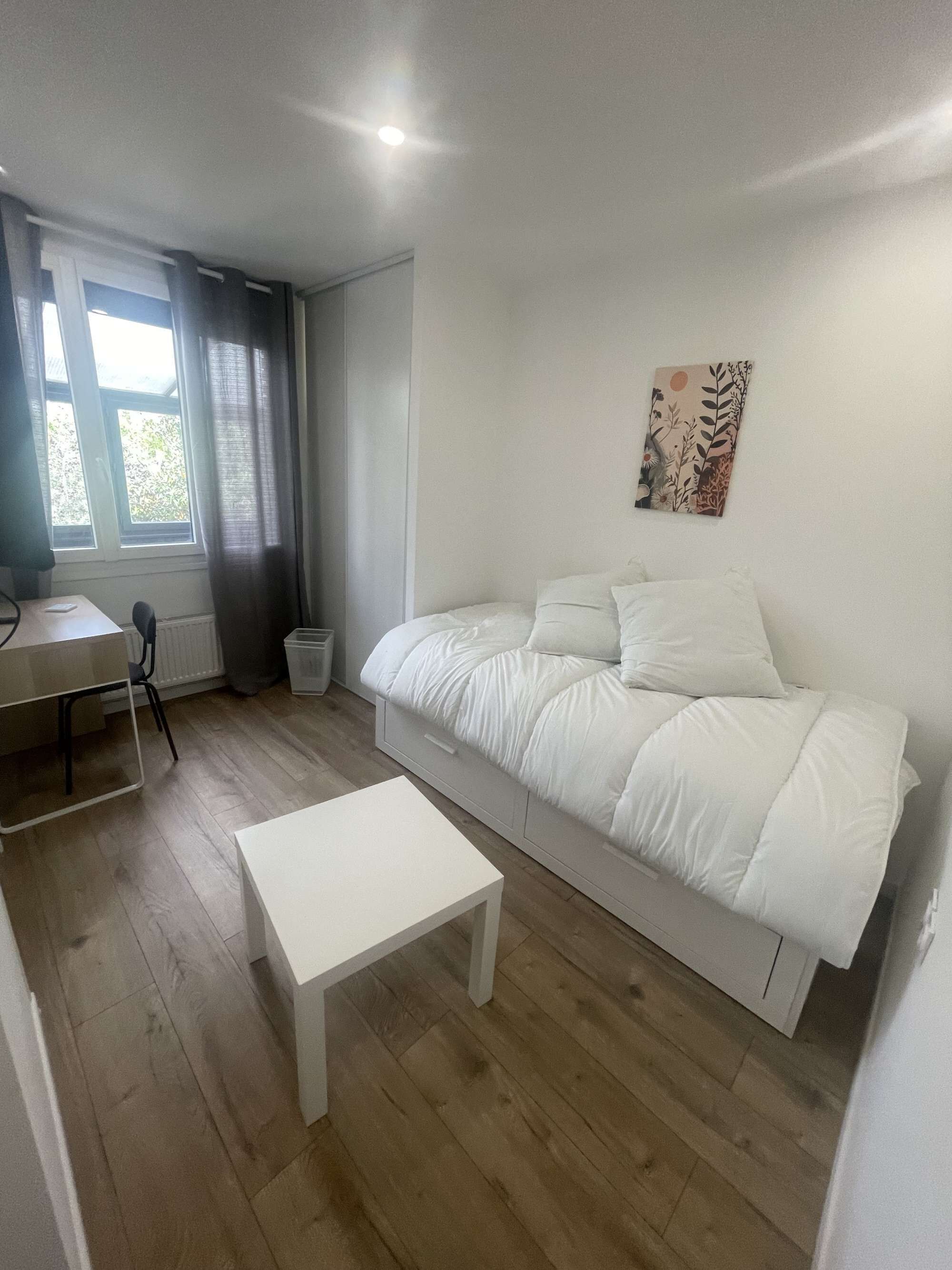A bedroom with a bed, a desk, and a chair.