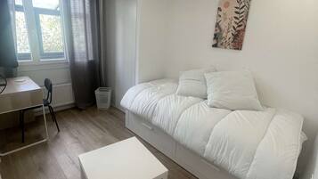 A bedroom with a bed, a desk, and a chair.