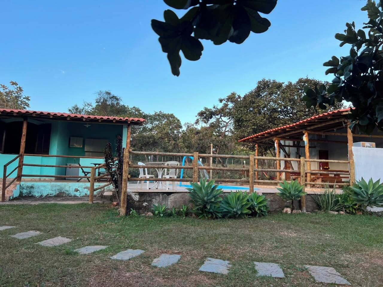 Um espaço com piscina, cerca de madeira e um pequeno jardim.