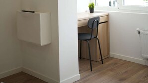 Et værelse med skrivebord, stol, radiator og et vindue med udsigt.
