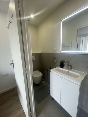 Et moderne badeværelse med toilet, vask og brusebad.