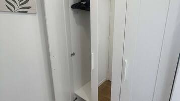 A room with a white wardrobe, a door leading to a closet, and a wooden floor.