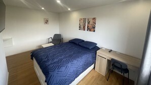 A bedroom with a bed, a desk, two chairs, and two wall-mounted artworks. - Cozy Private Room | Coliving 30min from Paris St-Lazare (Argenteuil)