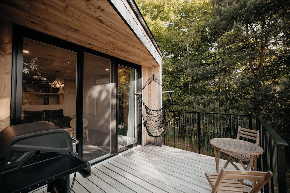 A wooden deck with a hammock, a table, and chairs.
