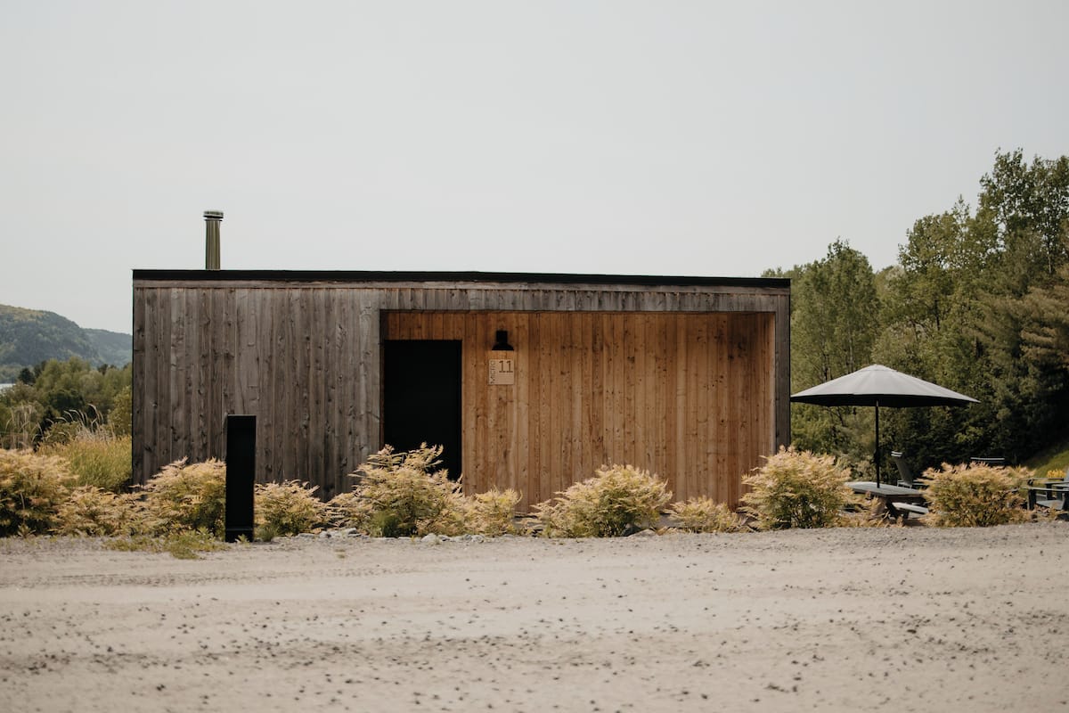 A rustic wooden building with a chimney, a door, and a small window.