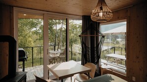 A wooden interior with a balcony, a table, chairs, a hanging light fixture, and a grill. - Nature Nature  (Saint-Jean-Des-Piles)