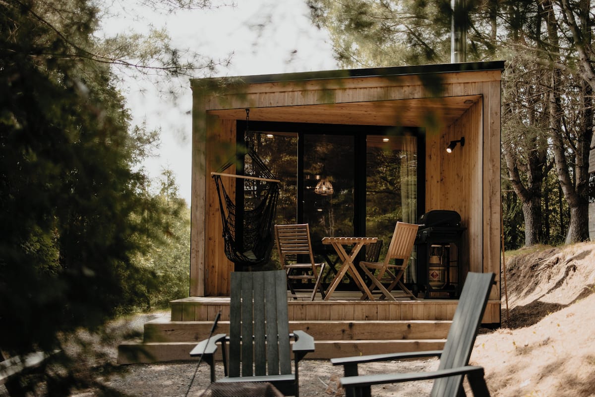 A wooden cabin with a porch, outdoor seating, and a hammock.