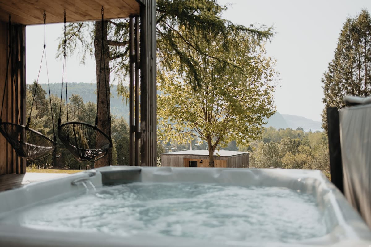 A hot tub with a view of a tree and mountains.