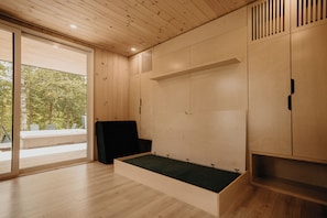 Ein moderner Raum mit Holzwänden, einer Schiebetür zu einem Außenbereich und eingebauten Stauraum.
