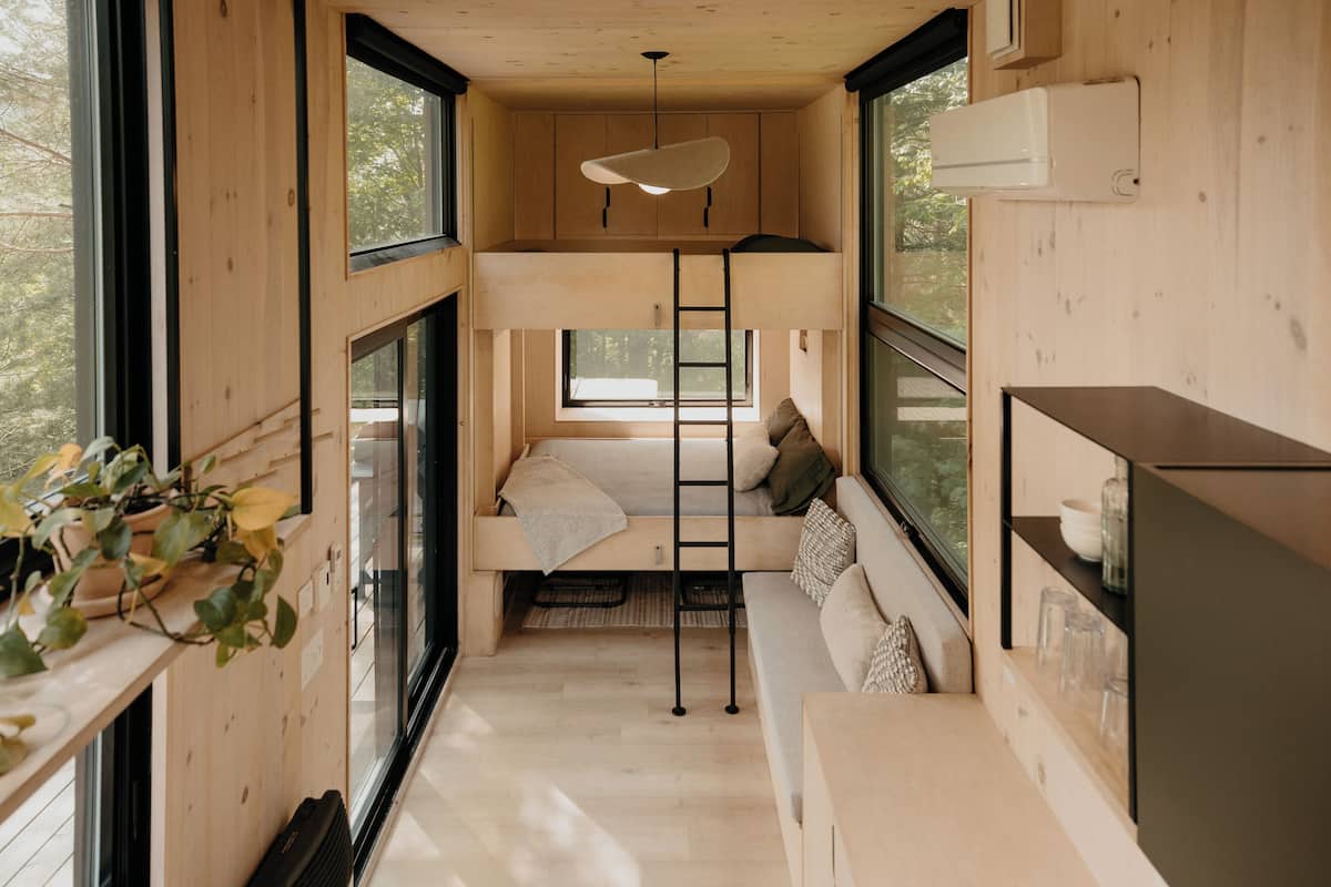A compact, wooden interior with bunk beds, a sofa, and a ladder.
