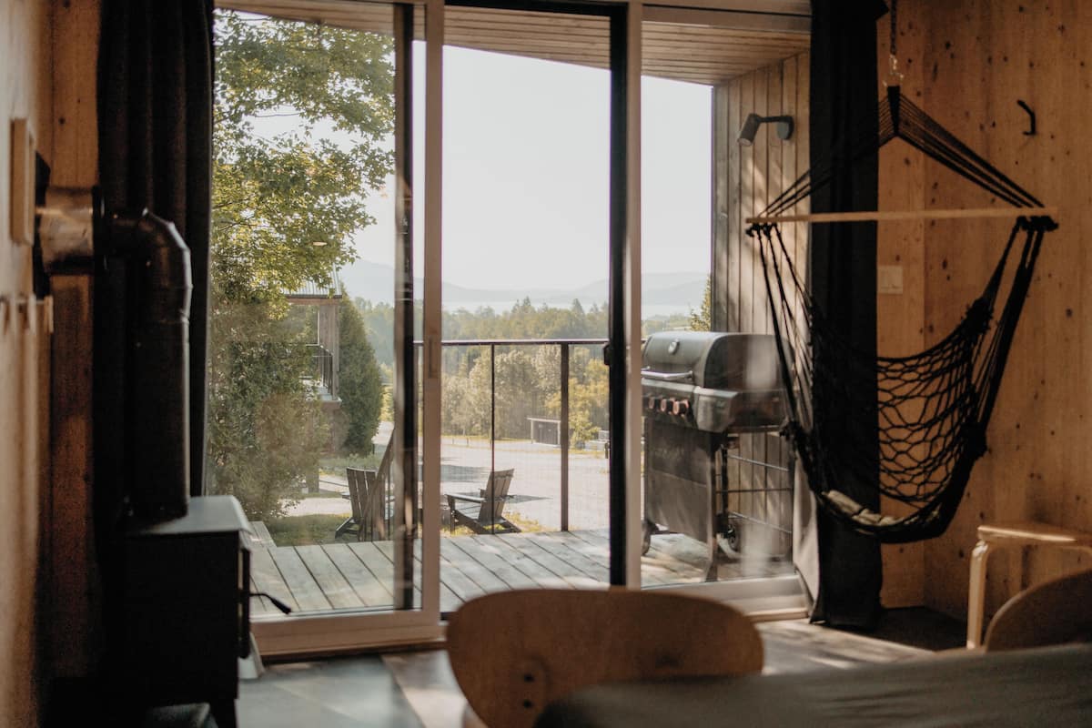 A room with a sliding glass door leading to a deck, a hammock, and a grill outside.