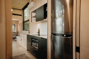 Una cocina compacta con electrodomésticos integrados, un pequeño rincón de descanso y un ventanal que proporciona luz natural.