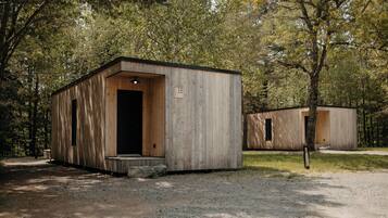 A wooden cabin with a door, a window, and a number sign.