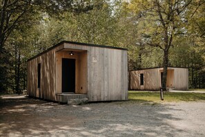 Una cabaña de madera con una puerta, un ventanal y un cartel con un número.
