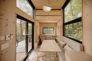A wooden interior with a large window, a table, and a bench.