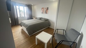 Un dormitorio con cama, escritorio, silla y obras de arte en la pared.