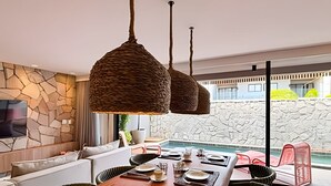 A modern dining area with a stone wall, a pool, and a view of a building.