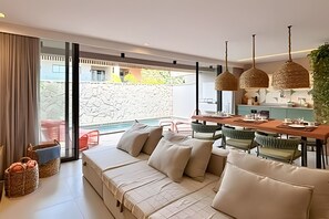 A modern living room with a sofa, dining table, and chairs. - Cond Triplex - By MME (Jacuípe)