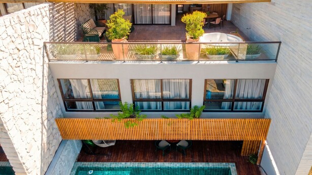 A modern multi-level residential building with a rooftop patio, a swimming pool, and a dining area.