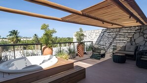A rooftop terrace with a hot tub, outdoor seating, and a stone wall.