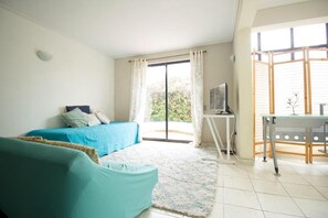 A bedroom with a bed, a sofa, a TV, and a sliding glass door leading to a balcony. - Amplia Casa en Reñaca Para 10 Personas (Vina del Mar)