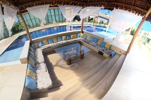 Ein Sitzbereich am Pool mit einem Glastisch und gepolsterten Bänken.