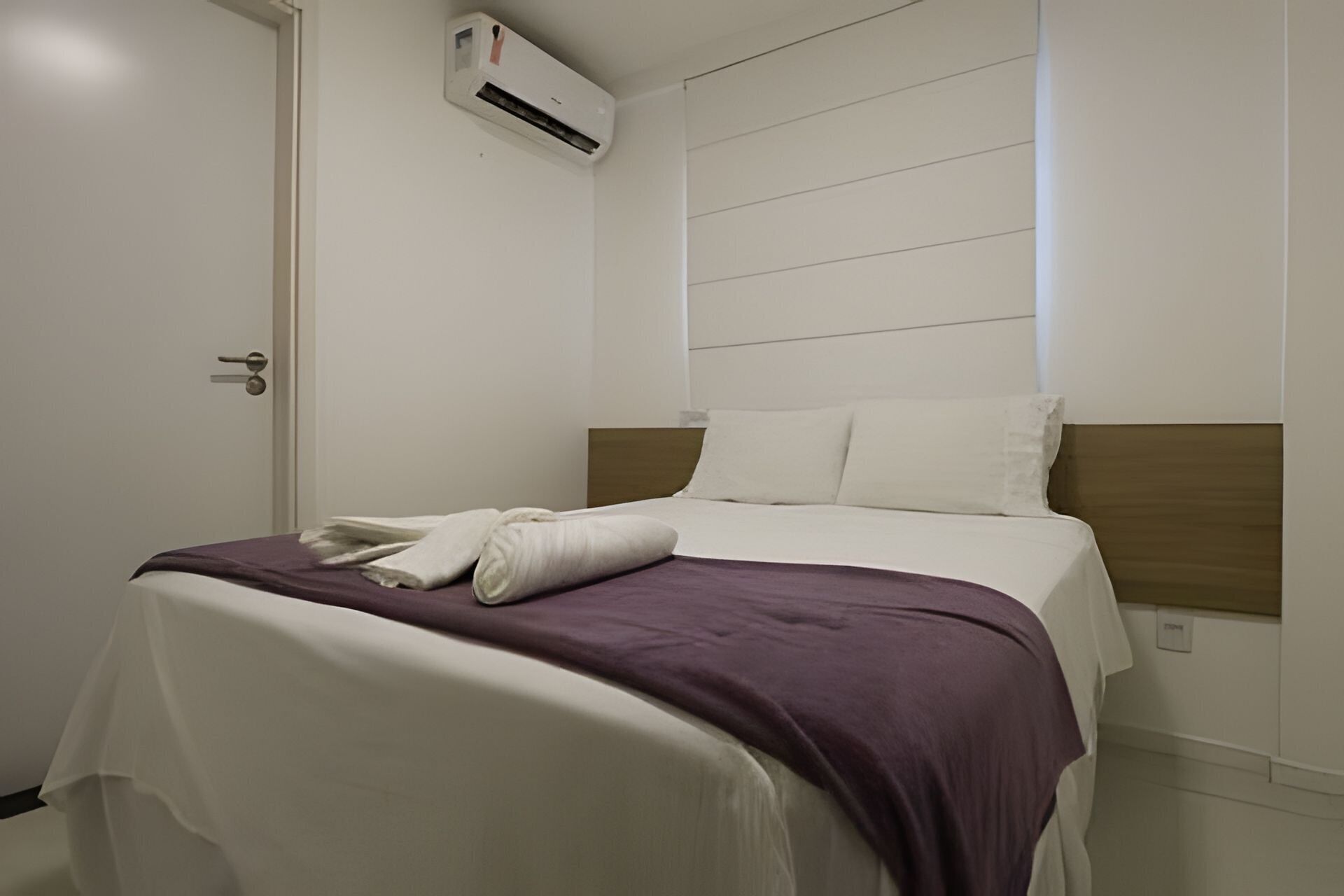 Ein Hotelzimmer mit einem Bett, einer weißen Klimaanlage und einer Tür.