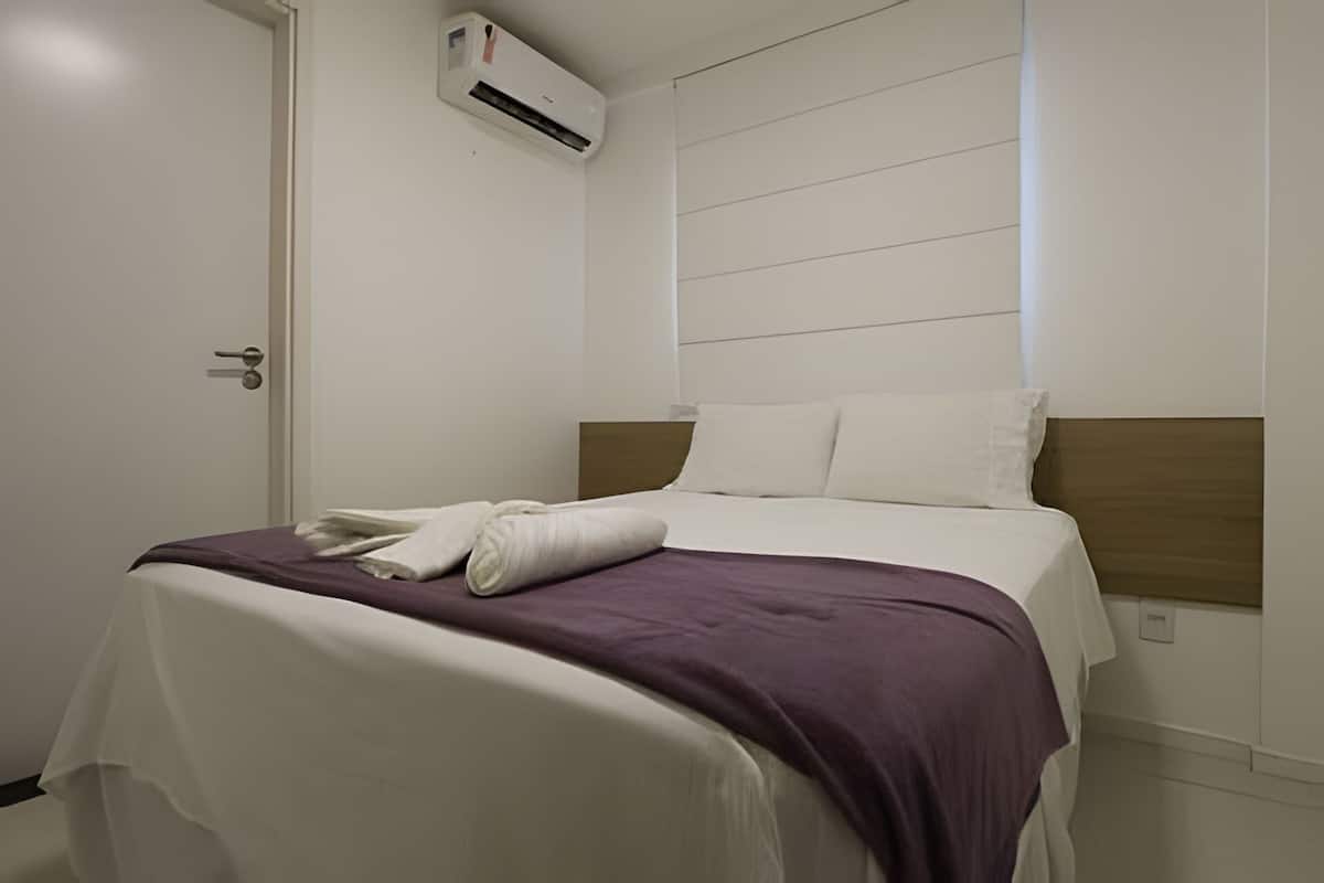 Ein Hotelzimmer mit einem Bett, einer weißen Klimaanlage und einer Tür.