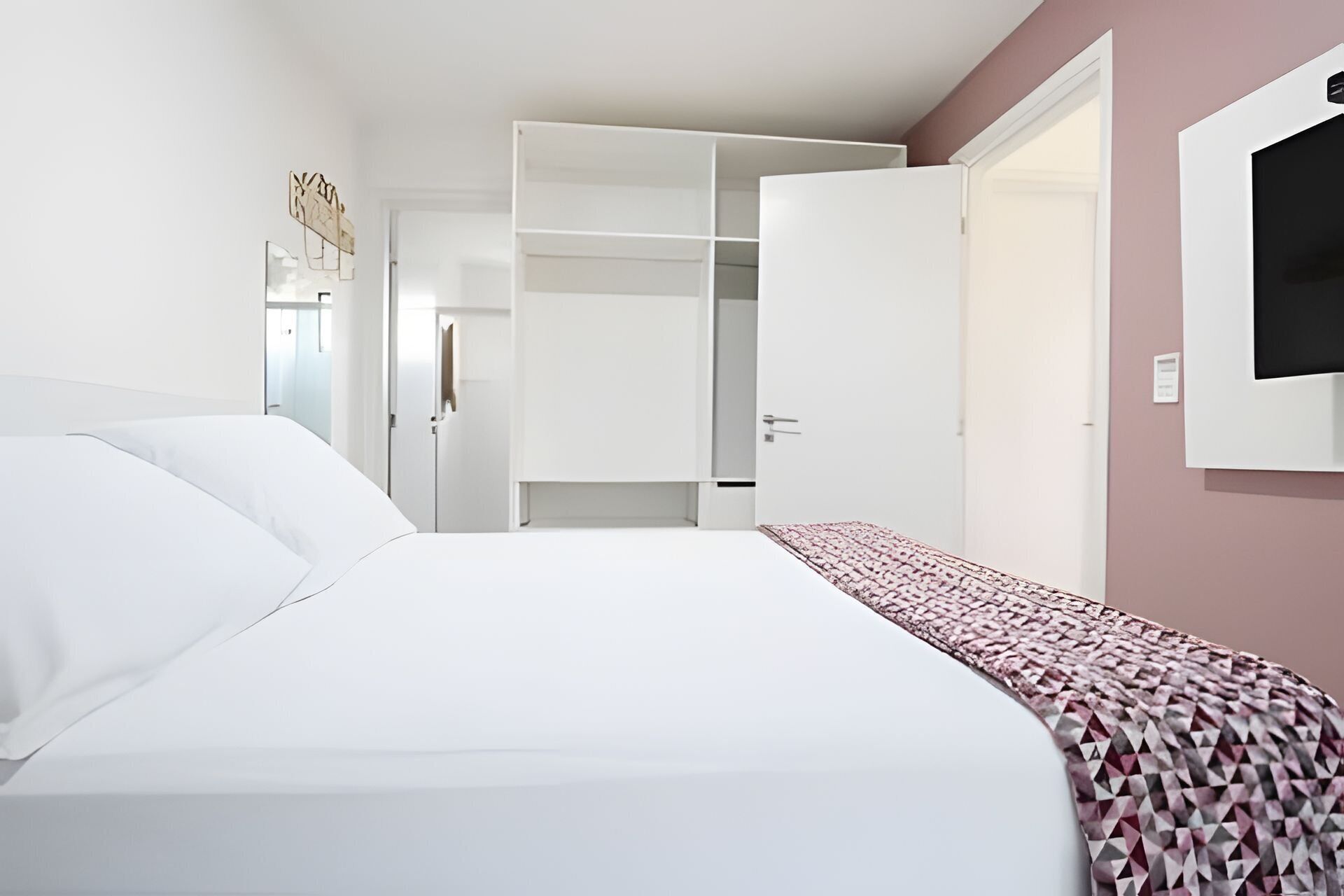 Ein Hotelzimmer mit einem Bett, einem Kleiderschrank und einem Fernseher.