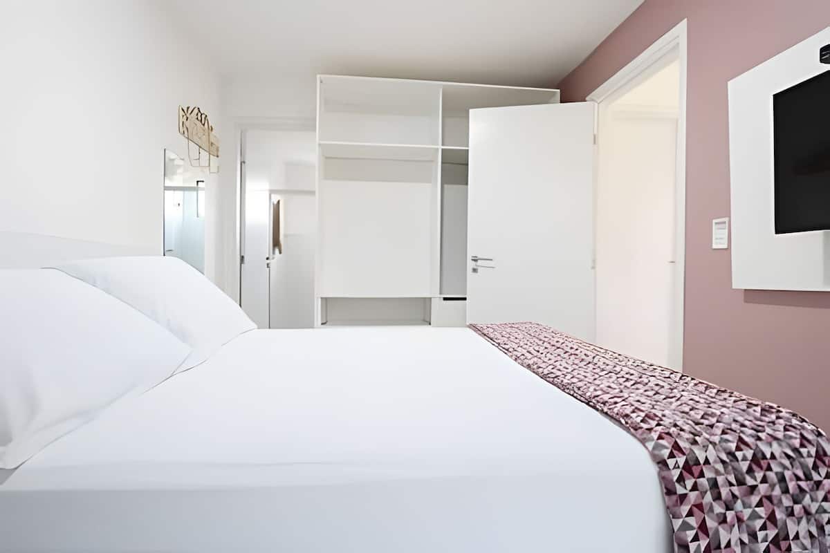 Ein Hotelzimmer mit einem Bett, einem Kleiderschrank und einem Fernseher.