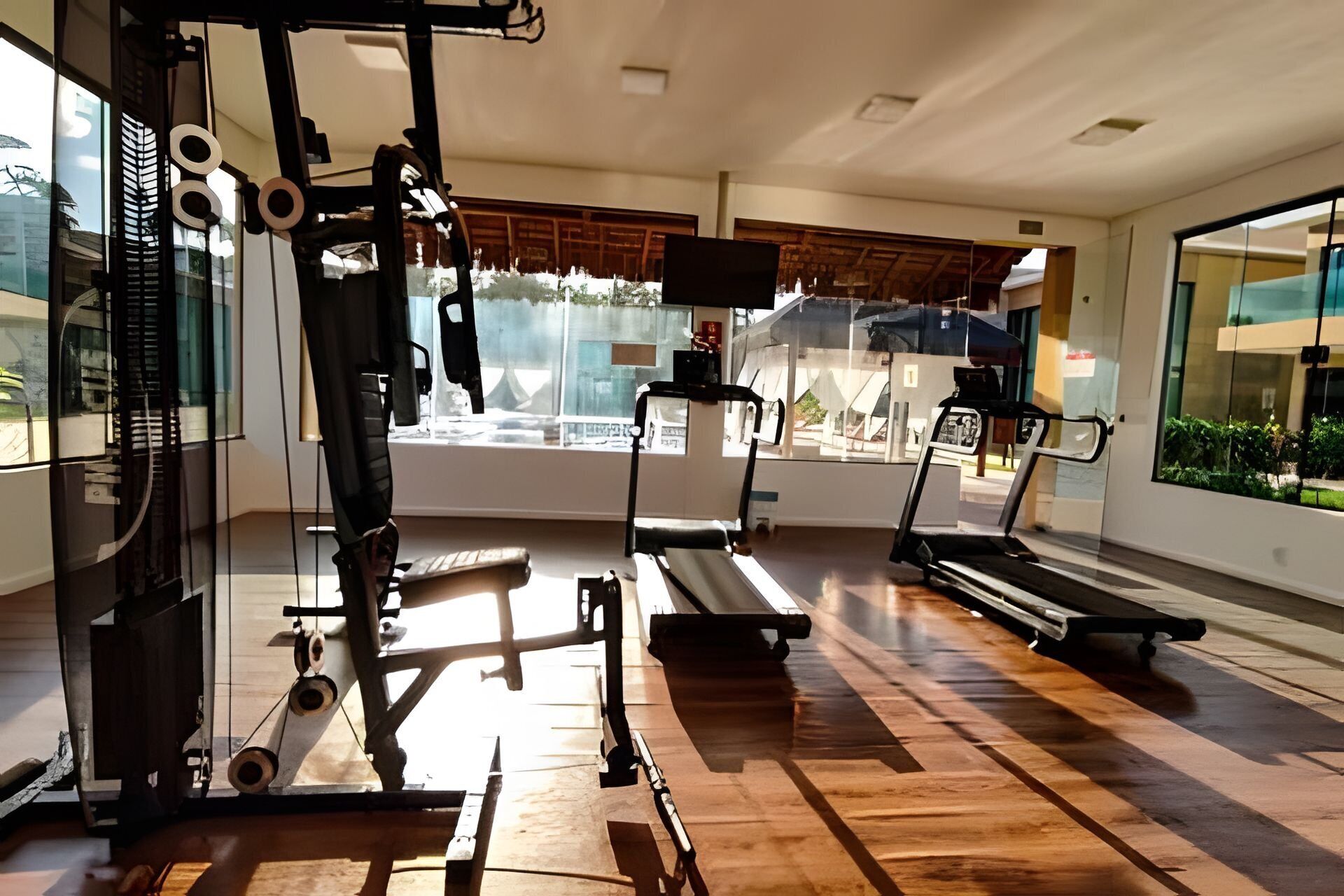 A gym with exercise equipment, a treadmill, and large windows.