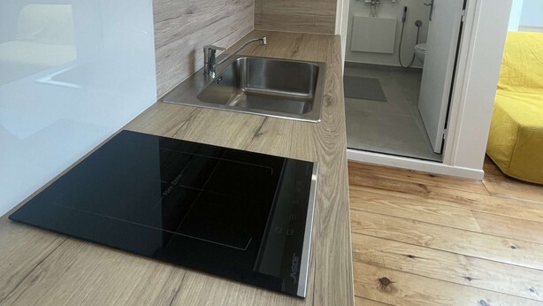 Una cucina moderna con piano cottura integrato, lavello in acciaio inossidabile e schienale in legno.