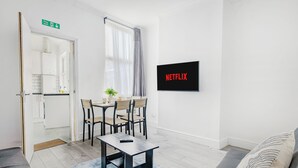 Un saló modern amb zona de menjador, un sofà, una taula de centre i una televisió penjada a la paret.