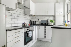 A modern kitchen with white cabinets, a black countertop, and a built-in oven. - NEW! 5BR House, free parking, near City Centre (Nottingham)