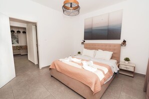 A bedroom with a bed, a nightstand, a wall-mounted lamp, and a painting. - SerenityOne - Centrally located Apt,SO19 (Agia Napa)