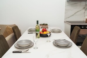 A dining table set with plates, glasses, a bottle, and a fruit bowl. - SerenityOne - Centrally located Apt,SO19 (Agia Napa)