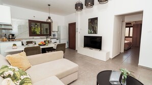 A modern living room with a sofa, dining table, and kitchen area. - SerenityOne - Centrally located Apt,SO19 (Agia Napa)