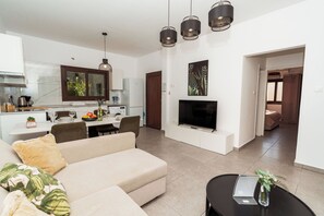 A modern living room with a sofa, dining table, and kitchen area. - SerenityOne - Centrally located Apt,SO19 (Agia Napa)