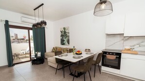 A modern kitchen with a dining table, chairs, a sofa, and an oven. - SerenityOne - Centrally located Apt,SO19 (Agia Napa)