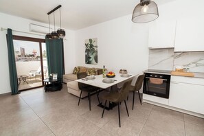 A modern kitchen with a dining table, chairs, a sofa, and an oven. - SerenityOne - Centrally located Apt,SO19 (Agia Napa)