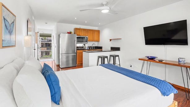 Une chambre d’hôtel moderne équipée d’un lit, d’une télévision, d’une kitchenette et d’un balcon.