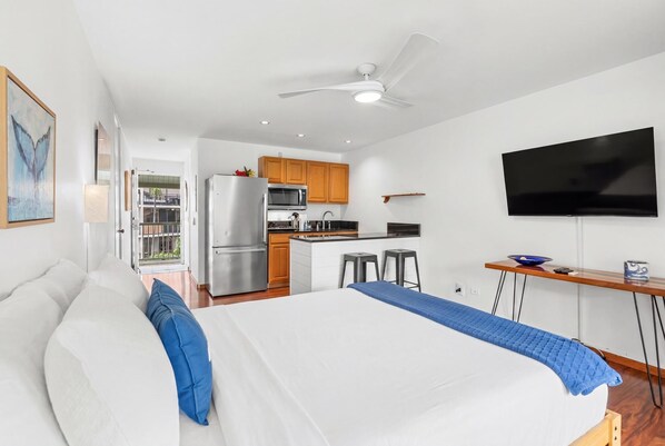 A modern hotel room with a bed, a TV, a kitchenette, and a balcony. - Kona Islander Inn#336 (Kailua-Kona)
